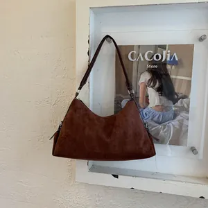 Detailed view of deep brown suede shoulder bag with thin straps on textured wall
