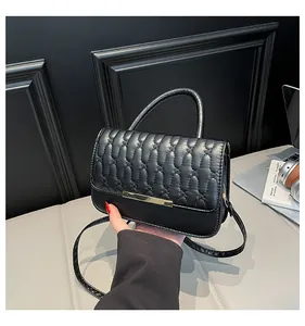 Macro detail of black quilted stitching and gold metallic bar buckle on handbag