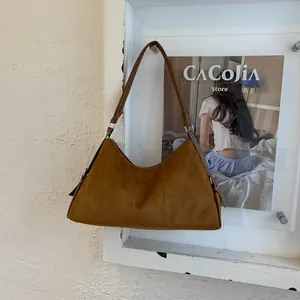 Detail shot of brown suede hobo bag with textured finish and crescent-shaped silhouette