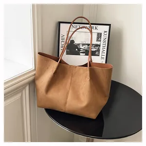 Détail d'un grand sac cabas marron en daim avec coutures verticales sur table ronde