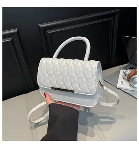 Close-up of white quilted handbag with golden bar lock and elegant wavy texture