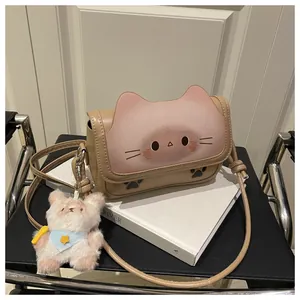 Détail d'un sac bandoulière couleur chameau avec tête de chat et pendentif ours peluche