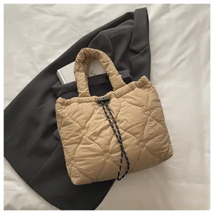 Detail of heart-quilted texture and woven drawstring on the beige bucket bag