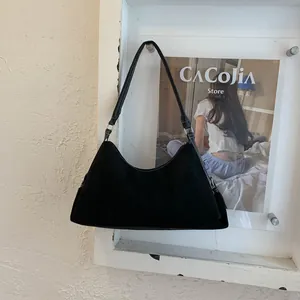 Detail of minimalist black suede shoulder bag with white contrast stitching and silver hardware