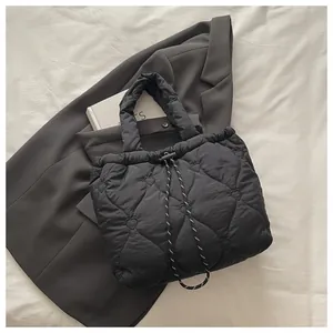 Close-up of heart quilted stitching detail and woven drawstring on black bucket bag