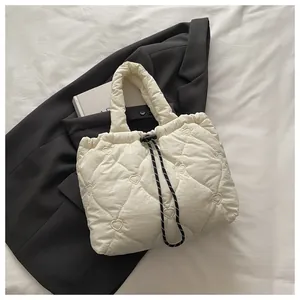 Close-up of cream quilted bucket bag with heart stitching and decorative drawstring detail