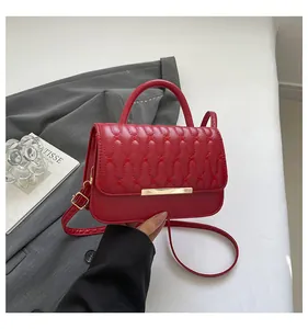 Detailed view of red quilted leather bag with wave embroidery and gold metal clasp hardware