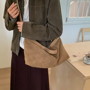 Detailed view of the brown suede tote bag with leather strap in a retro lifestyle setting