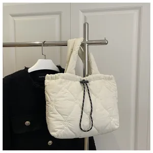 Detail of heart-shaped quilting and black drawstring closure on cream bucket bag