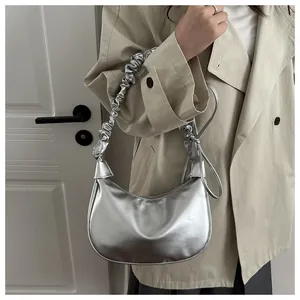 Sac hobo métallisé argenté avec anse plissée porté par un mannequin chic