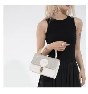 Detail of white leather handbag with sequined flap and golden rectangular clasp