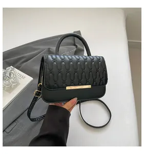 Close-up of black crossbody bag with wavy quilting and elegant gold metal hardware details
