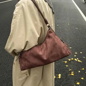 Deep burgundy suede baguette bag with slim shoulder strap shown in an autumn street setting