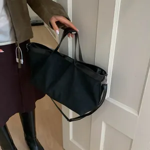 Detail of minimalist black tote bag with leather trim and detachable shoulder strap