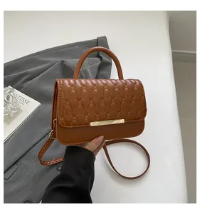 Close-up of caramel brown quilted handbag with wavy stitching and gold metal trim