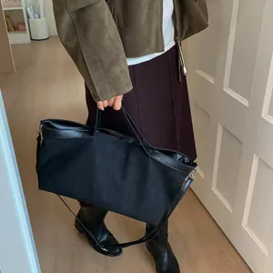Detail of a large black tote bag showing its matte texture and leather handle stitching