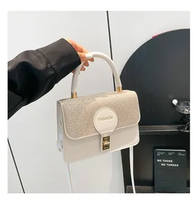 Detail showing beige small square bag with glitter flap and golden metal clasp handle