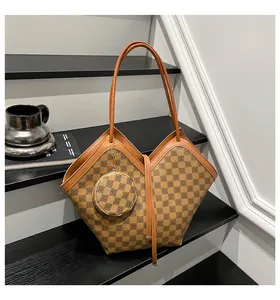 Detail view of brown checkerboard tote bag with floral print and round coin purse charm