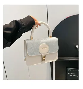 Detail of silver sequined flap on cream handbag with gold twist lock and fashion logo