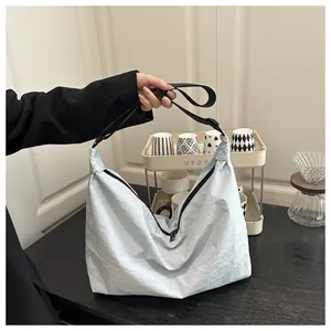 Detail of light blue nylon pillow bag with adjustable black strap and zipper closure