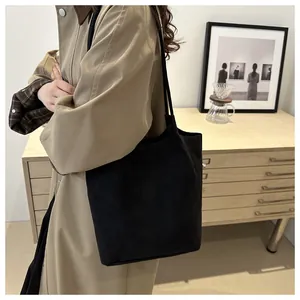 Minimalist black tote bag shown on model in a stylish indoor cafe environment