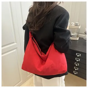Macro detail of large red nylon tote bag with black zipper and integrated shoulder strap
