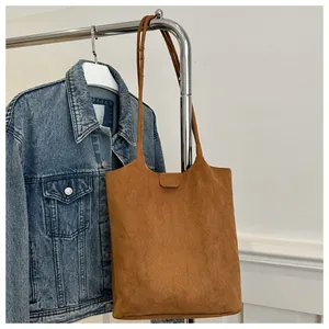 Detailed texture of brown suede tote bag featuring slim straps and a minimalist aesthetic