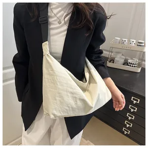 Detail of off-white nylon pillow bag with adjustable black strap and wrinkled texture