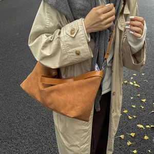Caramel suede tote bag detail featuring smooth leather trim and adjustable silver buckle strap