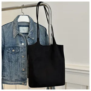 Detail of minimalist black matte tote bag hanging with slim shoulder straps and large capacity