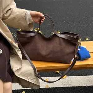 Detail of dark brown matte tote bag with leather handles on a park bench with autumn leaves