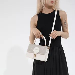 White French style handbag with glitter flap and gold lock shown on a female model