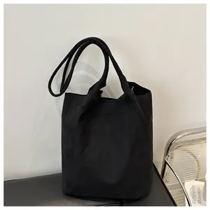 Detail of minimalist black matte bucket bag on a leather surface with a modern studio background