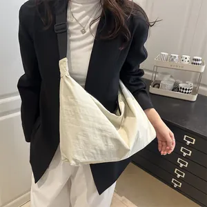 Minimalist cream white hobo bag with adjustable black strap worn by a female model