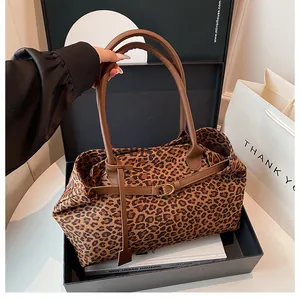 Detail of leopard print tote bag with brown leather handles and gold buckle on gift box