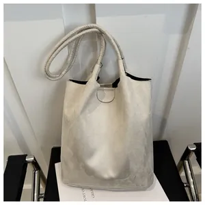 Minimalist beige suede tote bag with slim shoulder straps on a stylish black chair
