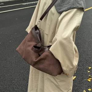 Close-up of retro brown suede tote bag with leather straps on khaki trench coat