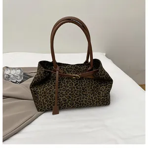Detailed macro of leopard print tote bag with brown faux leather handles and gold buckle