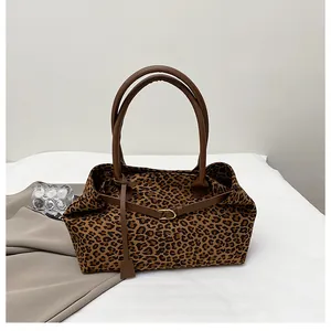 Close-up of leopard print tote bag fabric with brown leather handle and gold buckle detail