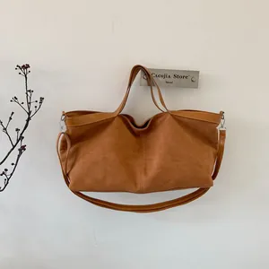 Detail view of the brown suede tote bag featuring sturdy handles and metal strap hooks