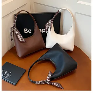 Détail de sacs à main en cuir en forme de croissant marron, blanc et noir avec foulards