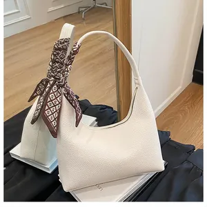 Détail du sac sous l'aisselle en cuir crème avec foulard en soie et fermeture éclair métal