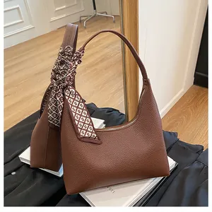 Gros plan sac hobo en cuir marron à motif litchi avec foulard en soie décoratif imprimé