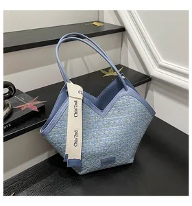 Close-up of light blue tweed bucket bag featuring V-shaped opening and brand strap detail