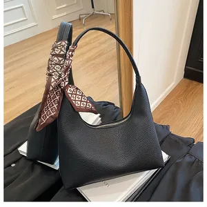 Gros plan d'un sac selle en cuir grainé noir avec un foulard décoratif sur la poignée