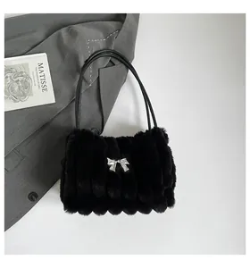 Gros plan du sac à main noir en peluche avec boucle argentée et texture à rayures