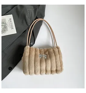 Détail du sac à bandoulière en fausse fourrure avec nœud en métal argenté et texture matelassée