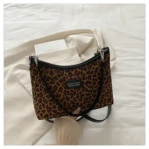 Macro detail of leopard print hobo bag with black leather trim on a minimalist background