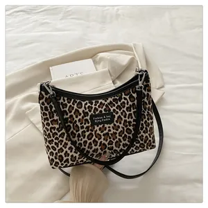 Detail of leopard print canvas bag featuring black leather trim and embossed brand patch