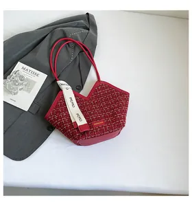 Detail of red tweed bucket bag with contrast leather trim and white decorative ribbon